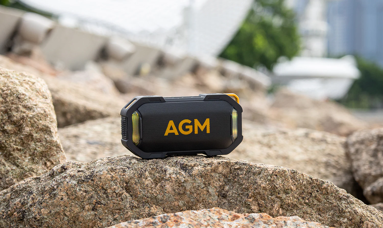 Schwarzer AGM MagROCK Lautsprecher mit gelbem AGM-Logo auf einem Felsen im Freien