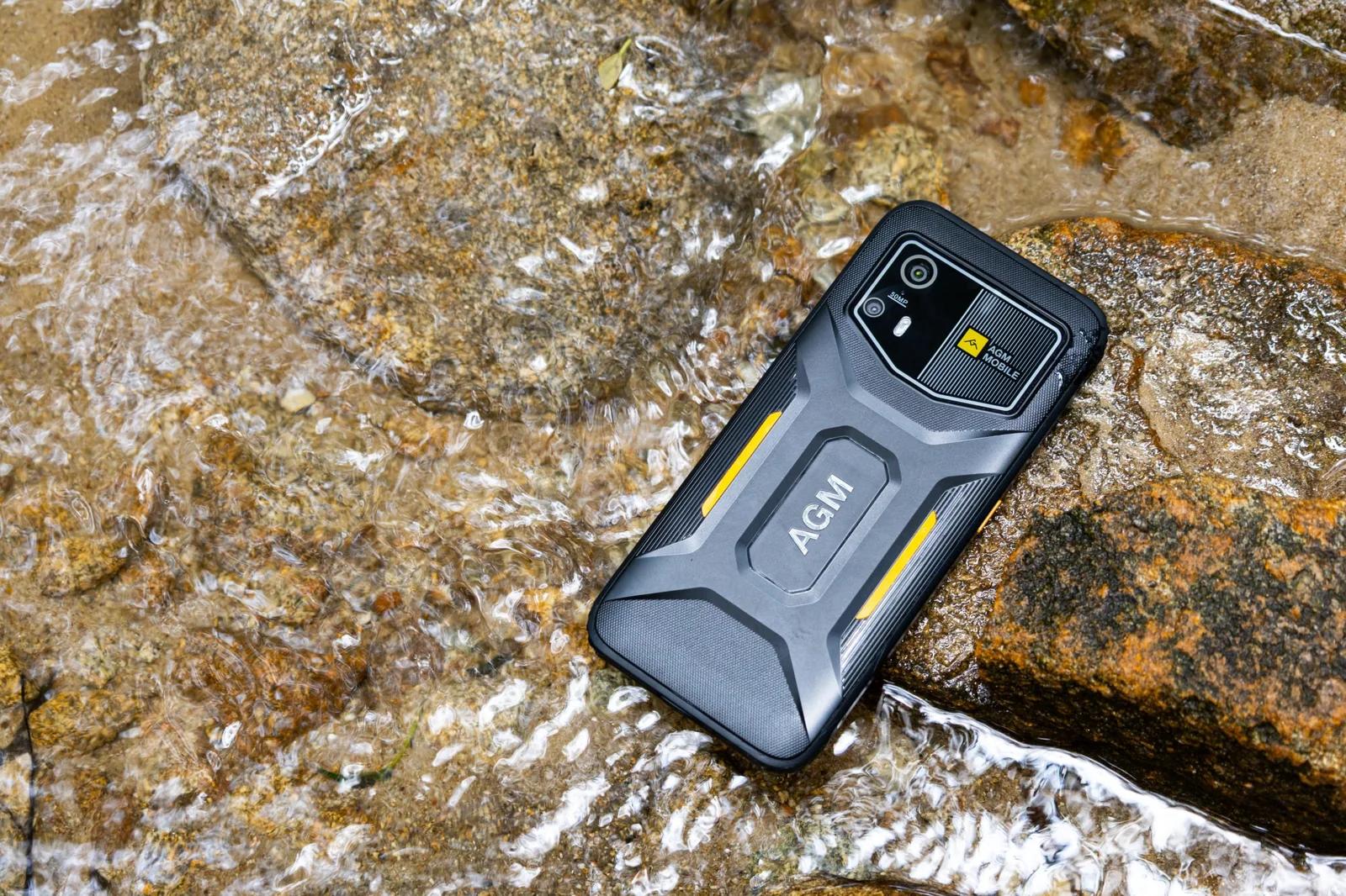 AGM H6 Pro mit sichtbarer Rückseite auf einem nassen Felsen im fliessenden Wasser